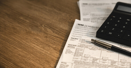 Obraz premium Calculator and pen placed on individual income tax return form with copy space on wooden desk for tax calculation, accounting review, financial reporting, and budget management workflow.
