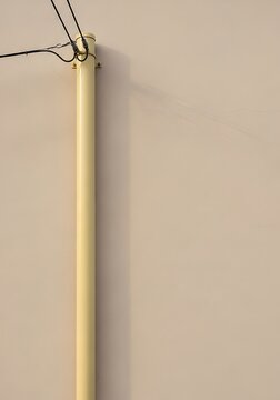 Minimalist yellow utility conduit pipe with electrical wires on a beige wall