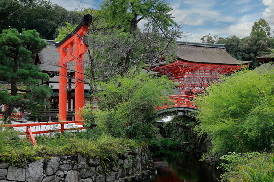 Red torii gate and arched bridge with stream at Kamigamo Shinto shrine, Kyoto, Japan