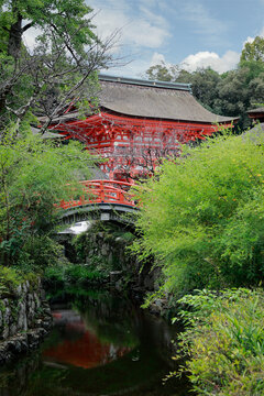 Red Japanese bridge over stream with pagoda at Kamigamo Shinto shrine, Kyoto, Japan
