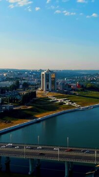 Vertical video. Cheboksary, Russia. Administration of the Head of the Chuvash Republic, a 17-story modernist tower with reflective glass facade, aerial forward approach over Cheboksary Bay under clea