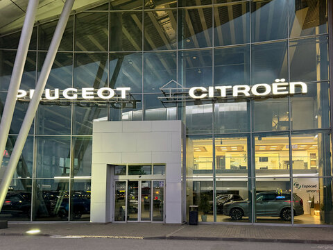 Dealer store Peugeot, Citroen at night. French car manufacturers. Peugeot Citroen brand logo on station with dealership sign text shop LED backlight. French car manufacturers brand. 