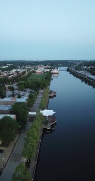 Vertical aerial drone video moving down with the river reflecting in downtown Elgin, Illinois.