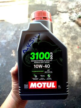 KUALA TERENGGANU MALAYSIA- MAY 25. 2026..Close-up of a person's hand holding a bottle of Motul 3100 Gold 10W-40 four-stroke engine lubricant for motorcycles and utility vehicles.