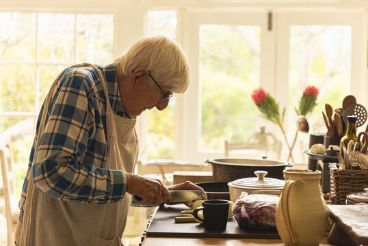 elderly man in light filled kitchen preparing a pot roast 