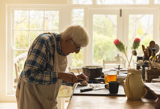 elderly man in light filled kitchen preparing a pot roast 