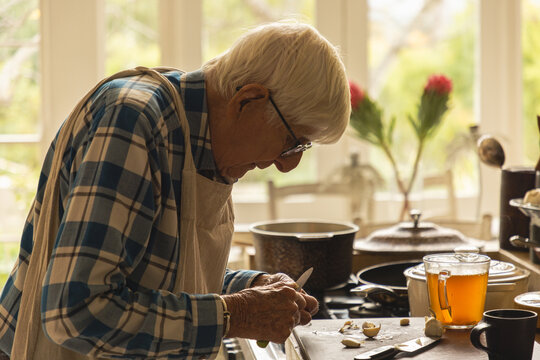 elderly man in light filled kitchen preparing a pot roast 