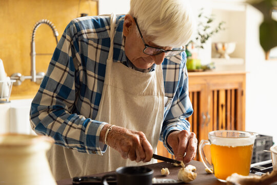 elderly man in light filled kitchen preparing a pot roast 
