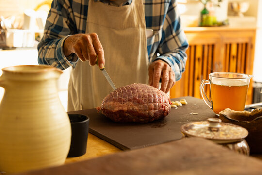 elderly man in light filled kitchen preparing a pot roast 