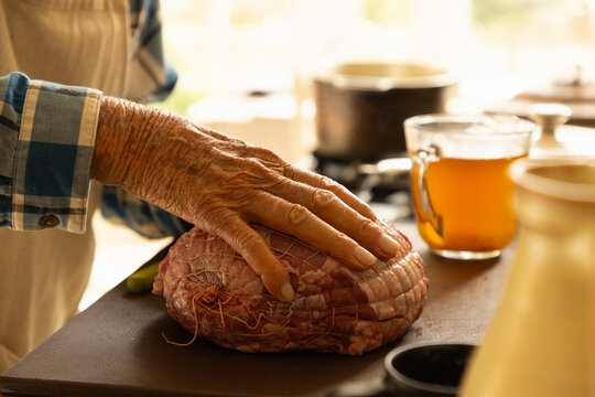 elderly man in light filled kitchen preparing a pot roast 