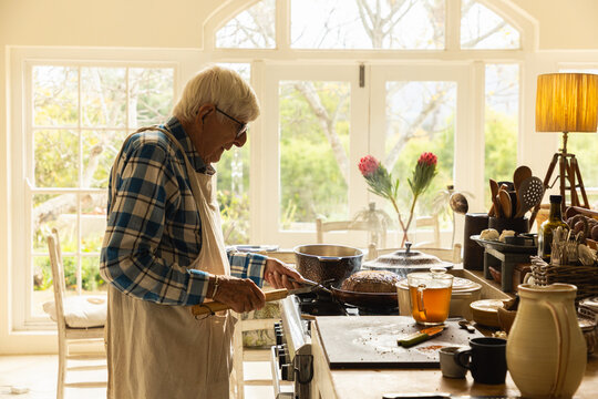 elderly man in light filled kitchen preparing a pot roast 