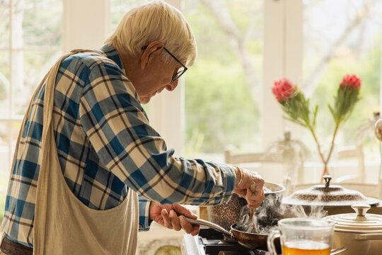 elderly man in light filled kitchen preparing a pot roast 
