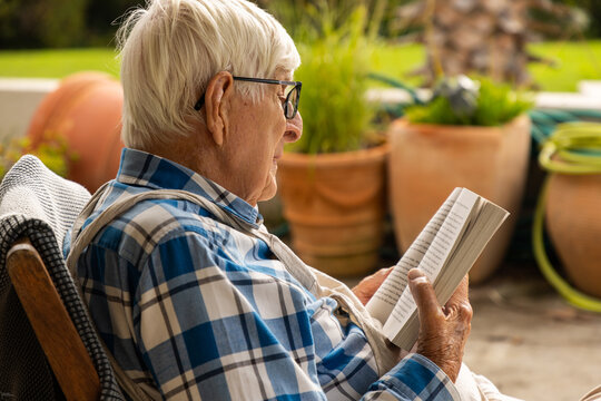 elderly man reading paperback book outdoors