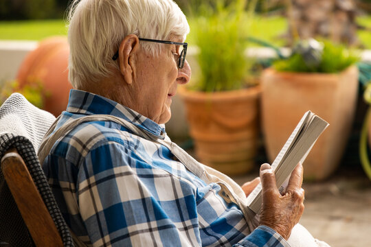 elderly man reading paperback book outdoors
