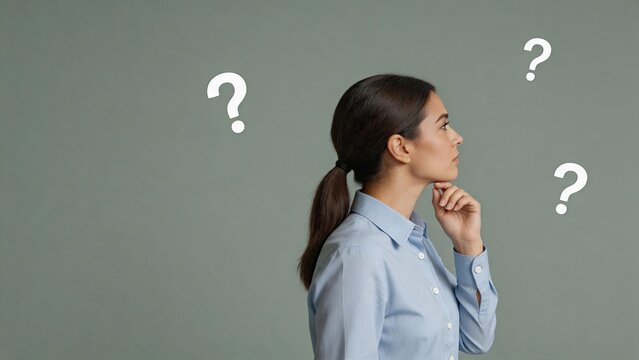 Profile of a thoughtful woman looking up at floating question marks on grey background, representing confusion, problem solving, decision making process and seeking answers to