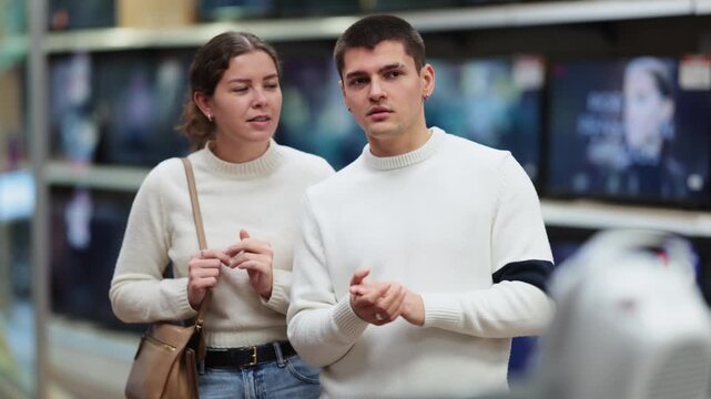  Young couple man and woman choosing plasma TV in home appliance store