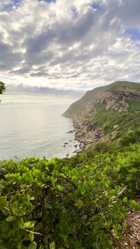 Mom with twin girls at scenic viewpoint on Robberg hiking trail. Vertical pan
