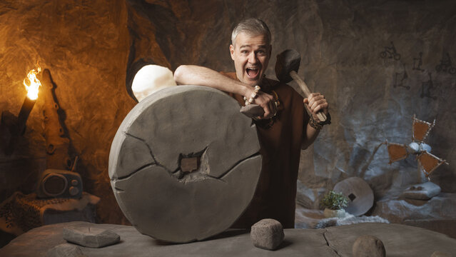 Proud prehistoric man inventing the first wheel