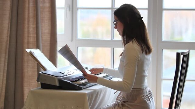 Woman playing music synthesizer while reading notes. Musician practicing keyboard composition. Online lesson study process and creative blog content development