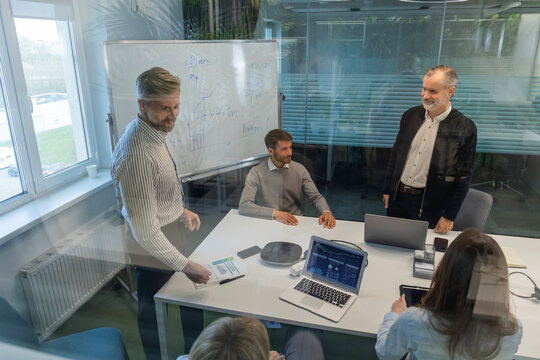 Creative business people, planning and meeting and brainstorming, ideas or strategy at office, view from glass wall.