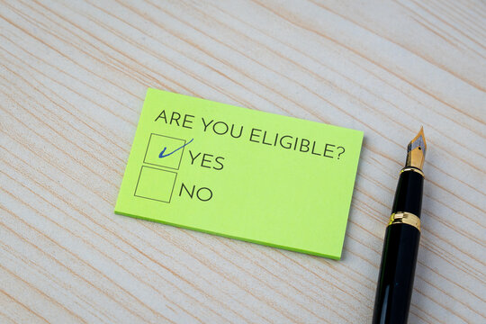 A note with the question Are you eligible? and a checked Yes box on a wooden desk. Qualification, approval, applications, and specific criteria concept.