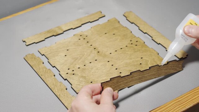 Hands Gluing Laser-Cut Wooden Pieces for Board Game Assembly