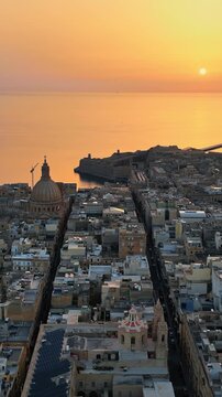 Aerial view of valletta city and carmelite church dome at sunset.