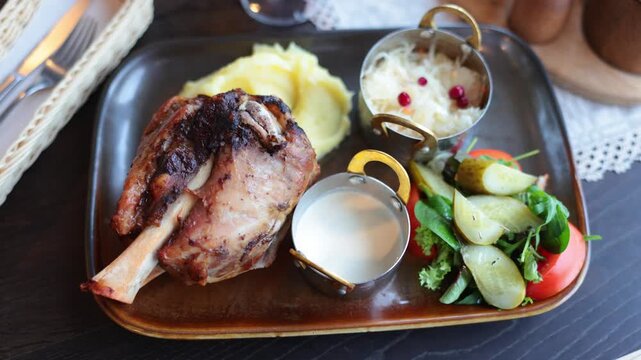 Baked pork hock - kepta karka, Lithuanian cuisine. Baked pork ham is served with mashed potatoes, pickles, vegetables, sauerkraut with cranberries. Baked meat with delicious amber crust