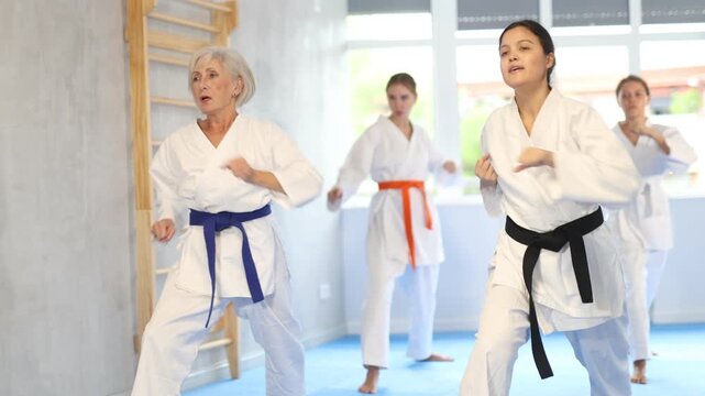  Group of women in kimonos train karate techniques in studio