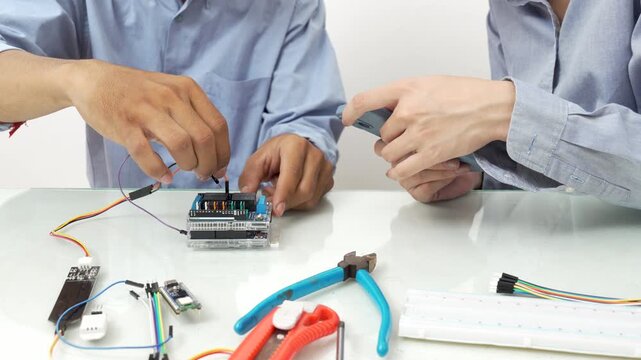 Close-up, Hand man and woman connecting soil moisture sensors to microcontroller