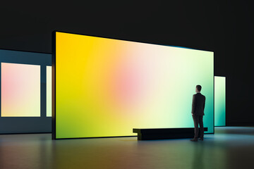 Large illuminated gradient display in modern gallery with a man observing the vibrant screen in a dark interior exhibition space showcasing digital art. © Who is Danny