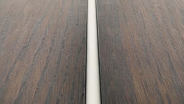 sealant. Smooth white sealant bead filling a gap between dark wood planks. safety posters, maintenance manuals, designed for precision metalworking and fabrication facilities, clarifies operation.