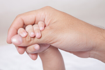 Obraz premium Close-up of Infant Fingers Grasping Father's Hand – Concept of Protection, Guidance, and Parental Bond