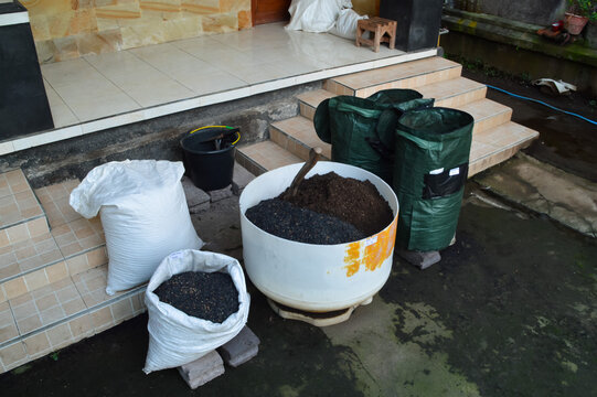 Extreme high right angle photograph capturing terrace soil mixing activity with compost materials, charcoal husk stock, and large planting media container.