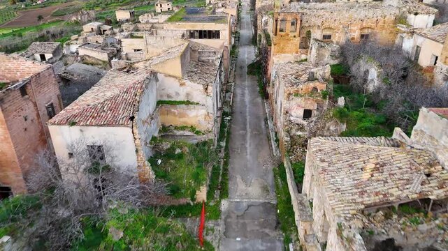 Aerial view of damaged buildings, open street, and hillside in Poggioreale Vecchia, an abandoned village in Sicily.
