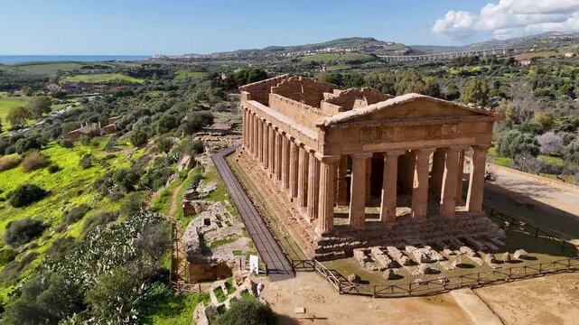 Aerial view of the Temple of Concordia at the Valley of the Temples in Agrigento, Sicily, with hillside city and olive groves.