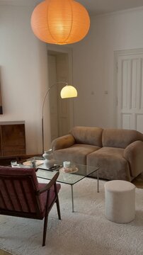 A minimalist and cozy living room interior with warm lighting from a round paper lamp.