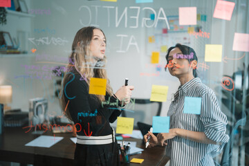 Colleagues Brainstorming Ideas with Sticky Notes on Glass Board © Kornkanok