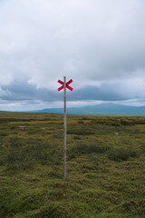 Fototapeta premium Vast Arctic Tundra Landscape in Swedish Lapland with Dirt Hiking Trail and Red X Trail Marker near Kvikkjokk along Kungsleden in Norrbotten Sweden