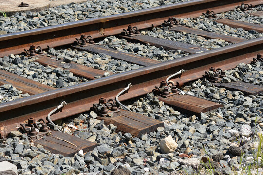 A detailed close up view of steel railway tracks with wooden sleepers stone ballast and copper ground bond cables