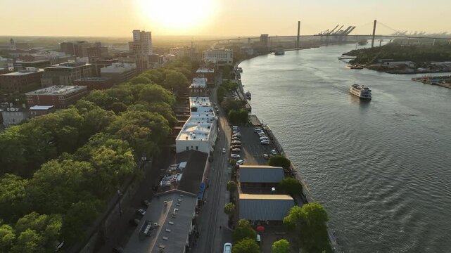 Cinematic drone footage of Savannah's River Street area, with a classic paddlewheel riverboat docked along the historic waterfront and the city's heritage on full display.
