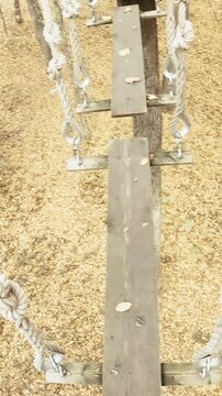 Adventure park walk between wooden hanging planks person POV