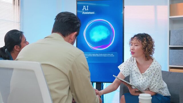 A professional East Asian business woman gestures actively while leading a tech presentation about an AI Assistant system on a vertical monitor, as her multiethnic male colleagues hold a laptop 