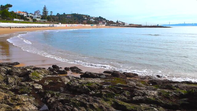 Scenic View of Caxias Beach in Oeiras, Portugal with the Atlantic Ocean Waves and Distant 25 De Abril Bridge