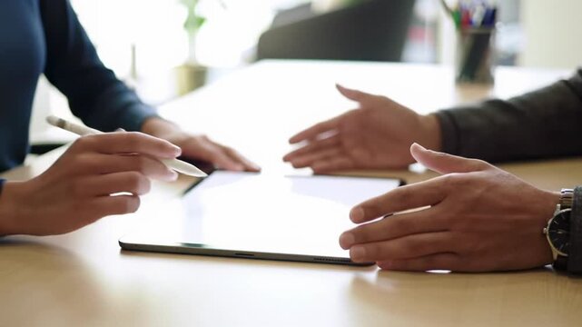 Professional hands in business-casual attire use a stylus on a blank tablet, gesturing ideas on a sleek desk with a blurred corporate office background. Concept of professional teamwork and innovation