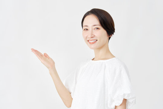 手のひらで左側を差すミドルエイジ女性　白背景