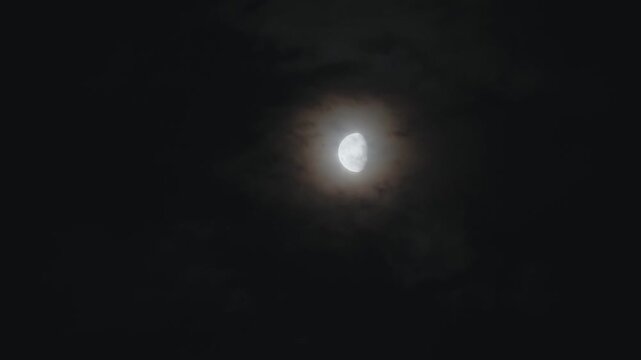 Timelapse of Bright moon glowing in night sky with clouds, atmospheric scene capturing natural satellite, night landscape and calm celestial environment with soft light and dark tones