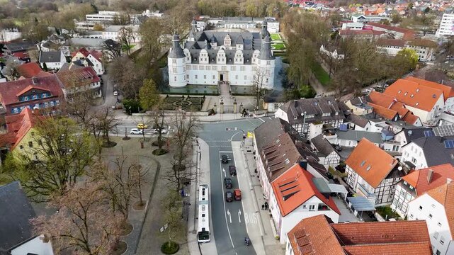 Wide aerial panorama of Schloss Neuhaus, landscaped garden, moat, parkland, and cloudy sky in Paderborn, North Rhine-Westphalia, Germany.