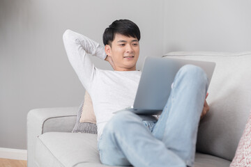 Young man relaxing on sofa using laptop at home