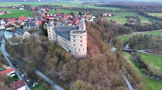 Evening drone view of Wewelsburg Castle at sunset with rural fields, forest, and historical Nazi era associations in Germany.